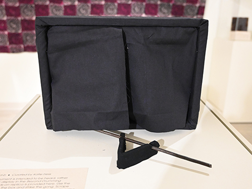 A black box with a curtain and a metal stick.