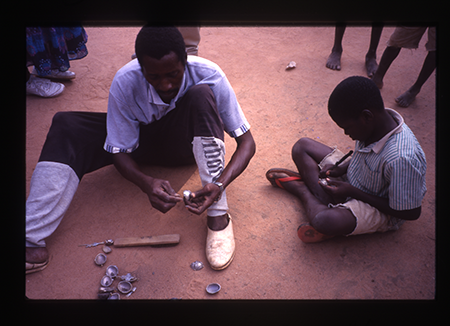 two people cleaning miniature brass masks