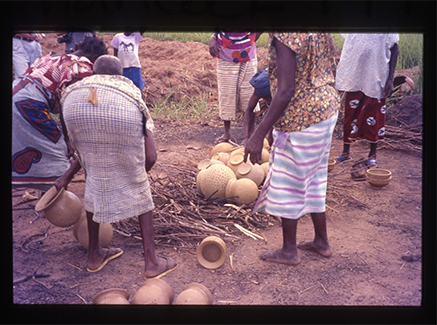 women building a fire to fire pots