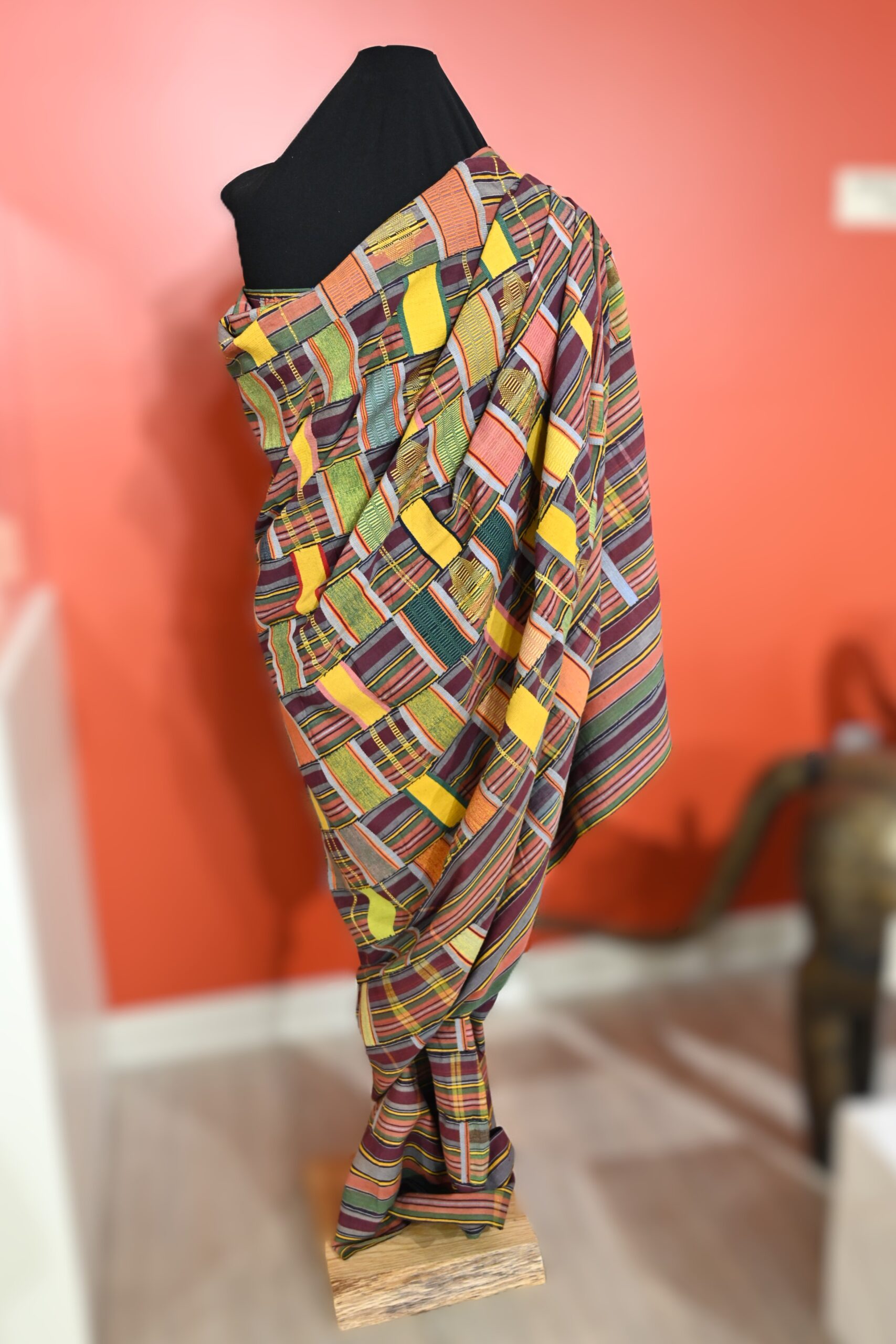 Mannequin with multicolored textile wrapped over one shoulder