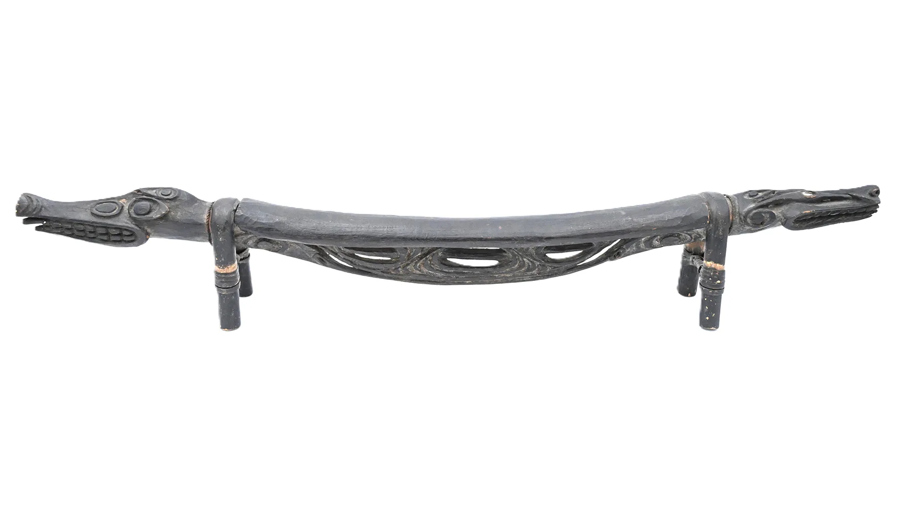 long wooden headrest with crocodile heads on each end