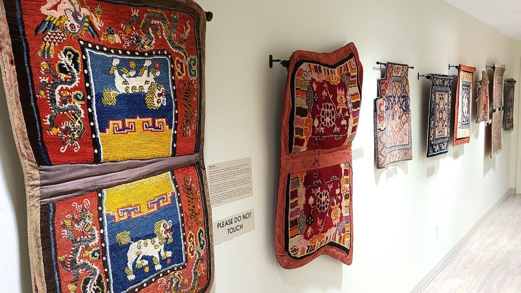 Saddle rugs displayed on a long wall