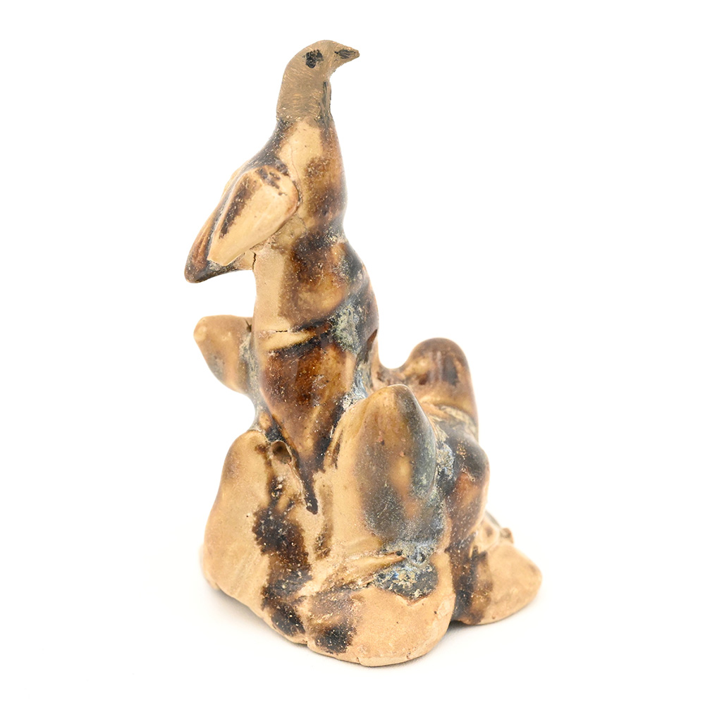 Miniature ceramic figure of a bird perched on rocks
