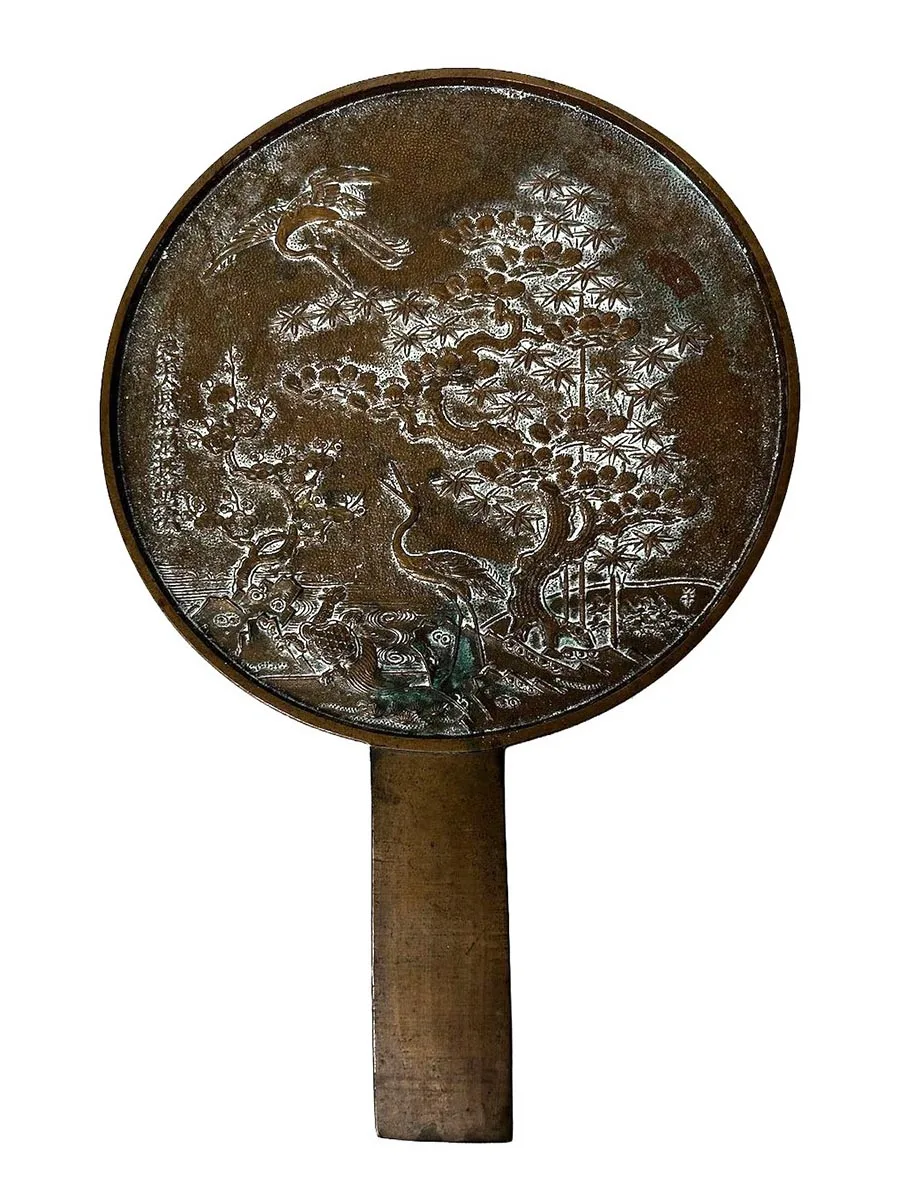 brass mirror with raised design on the back.