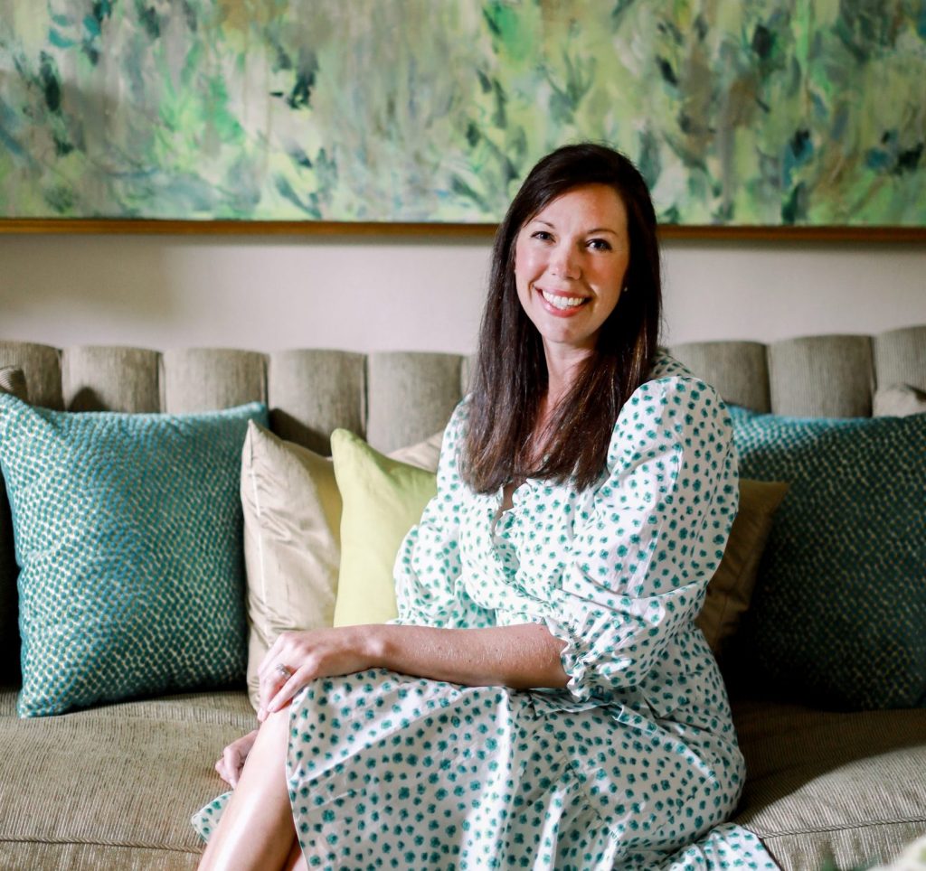 A woman sitting on a sofa in front of a painting