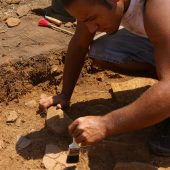 WFU student in Portugal using paint brush to remove debris from pottery.