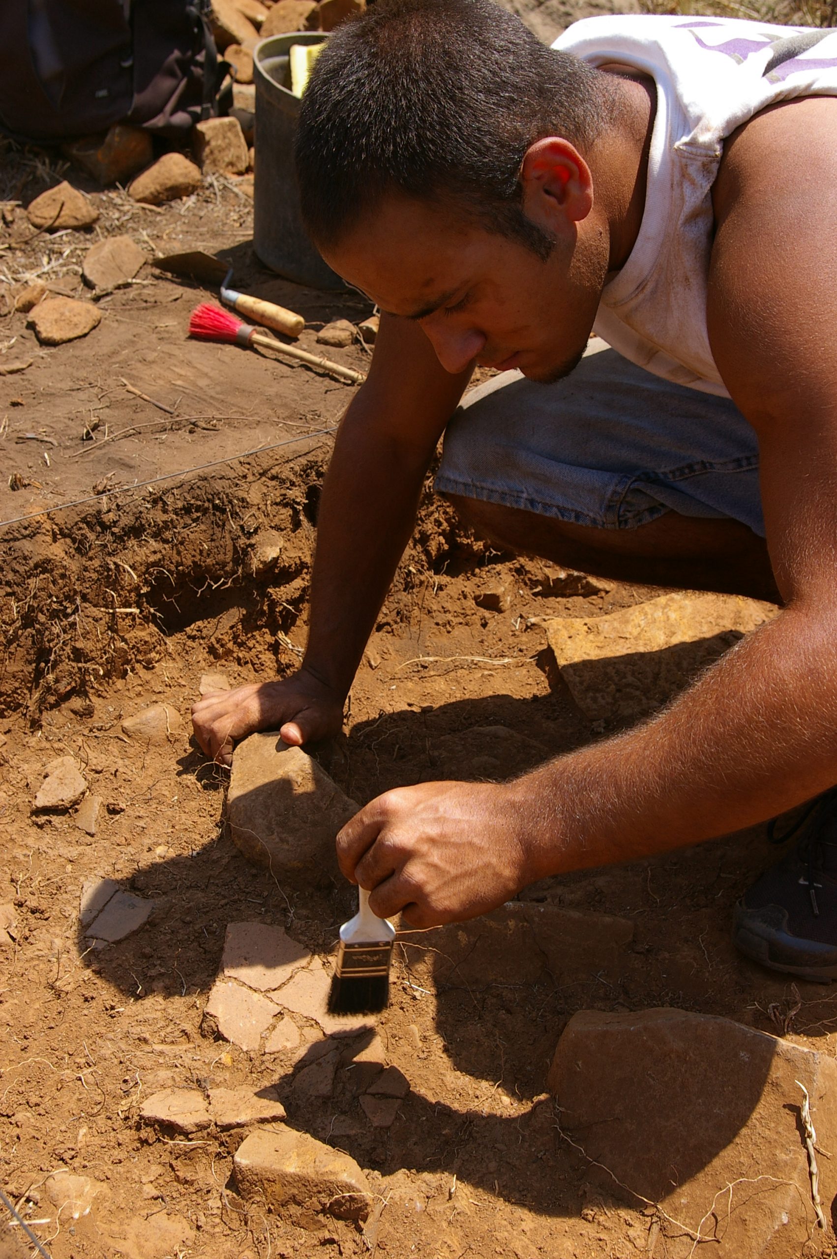 WFU student in Portugal using paint brush to remove debris from pottery.