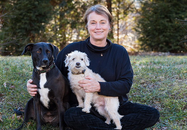 Jeanne Matthews Sommer with two dogs sitting on the grass