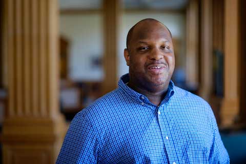 Shoulder-up in a blue shirt, Christian Burris ('93), godson of Isaac Sims ('75) and serials acquisitions editor at ZSR Library