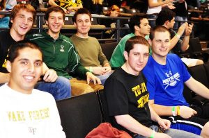 A group of young men smile at camera during a Wake Forest basketball game.