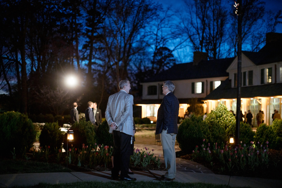 Two men stand facing Reynolda House at dusk