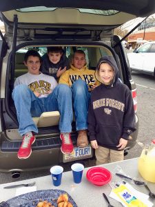 Young Luke Berry sits with friends in the back of a car at a Wake Forest tailgate