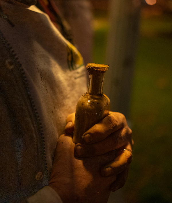 Hands hold a bottle filled with dirt