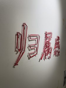 Red string forming letters in the Hex Li exhibit on the wall