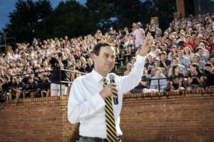 John Currie speaks to a crowd of students wearing a gold and black striped tie