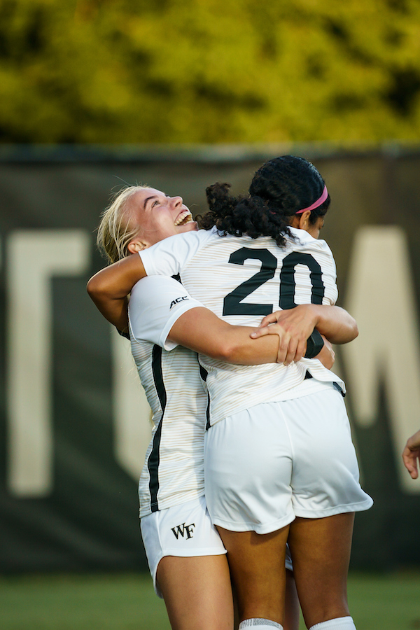 Wake Forest women's soccer players hug in celebration at Spry Stadium during a game against Loyola.