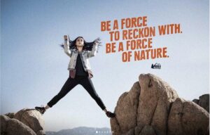 An REI ad shows a girl with legs on two rocks and the words "Be a force to reckon with , be a force of nature'