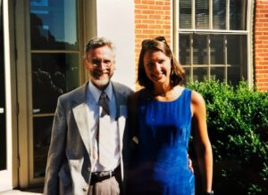 Dr. Stacy Wentworth in a blue dress stands next to physics professor Bill Kerr, one of her respected professors.