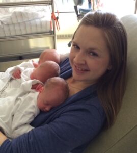 A smling Jill Snyder Kerr holds her three newborns on her chest