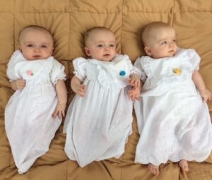 The Kerr triplets in white baptism gowns