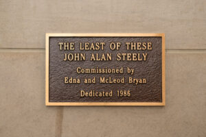 Plaque that reads: "THE LEAST OF THESE JOHN ALAN STEELY Commissioned by Edna and McLeod Bryan Dedicated 1986"