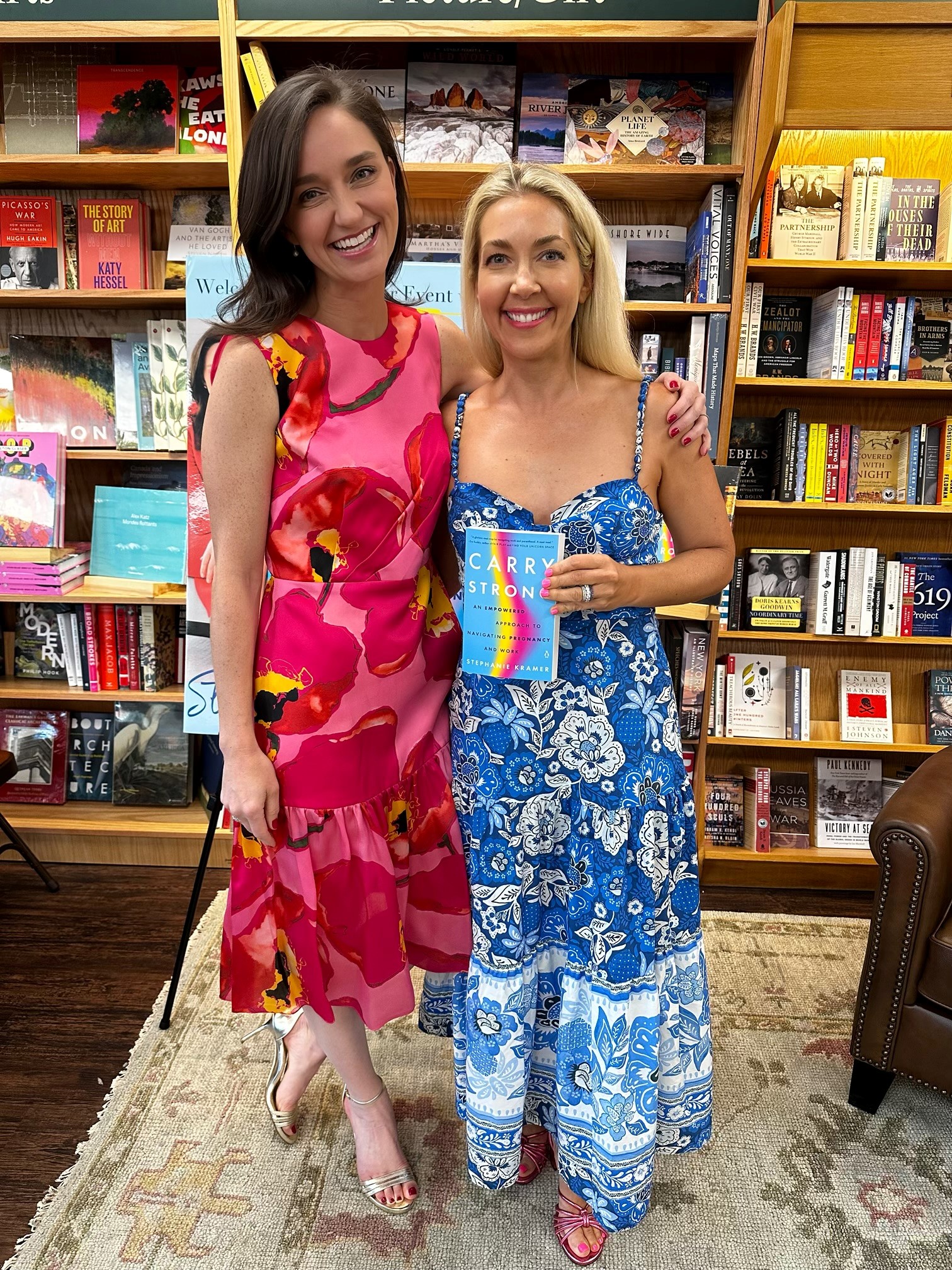 Stephanie Dishart Kramer ('04) stands next to Kate Farber Gold ('04) in front of bookshelves. 