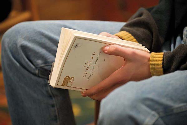 Hands holding a book. The book cover reads "The Leopard."