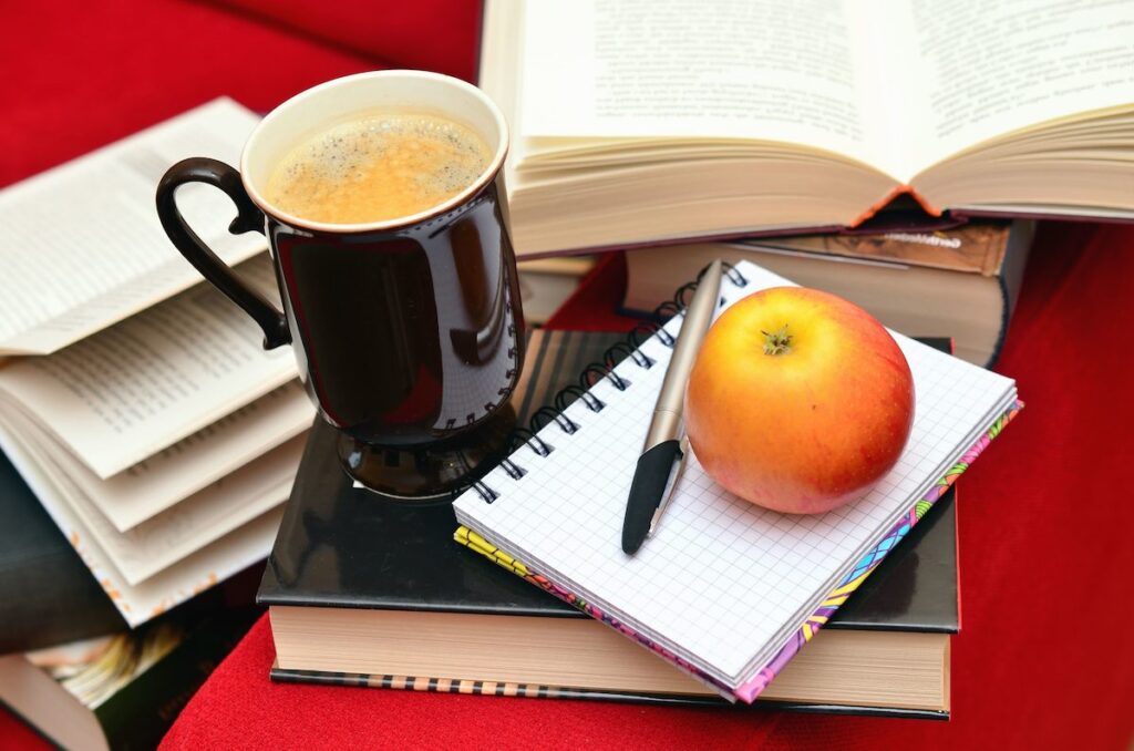apple sitting on pile of books with chalkboard education teaching learning