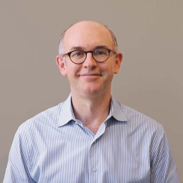 Headshot of Doug Schaller. He wears a blue and white striped shirt.
