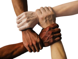 Four hands from four different people holding on to one another's wrists in unity