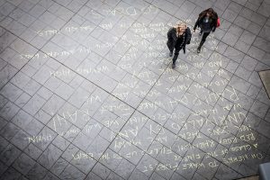 Students walk across sidewalk on top of chalked text of the Wake Forest Fight Song