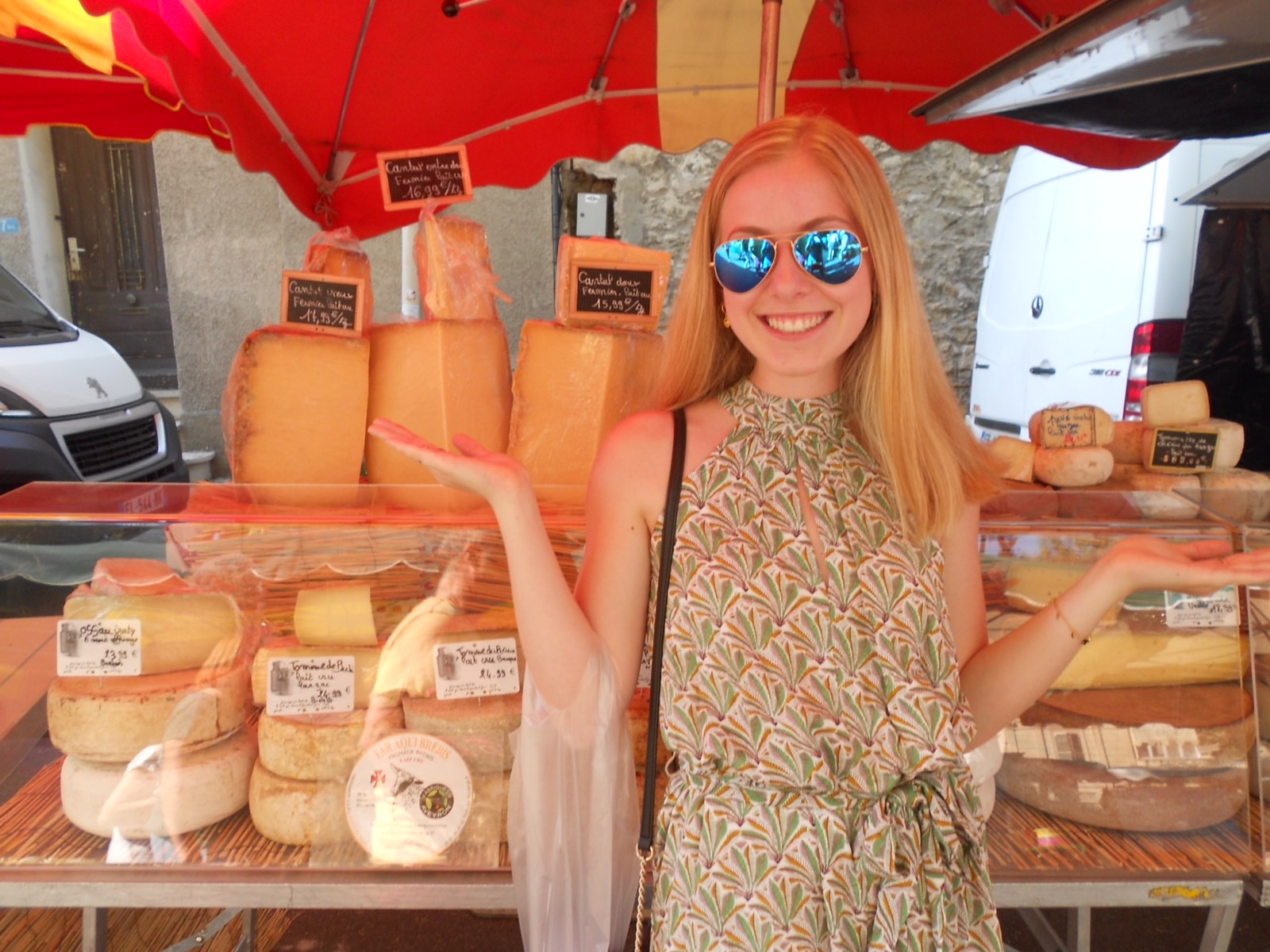 A student standing in front of a cheese maker's stall at a outdoor market