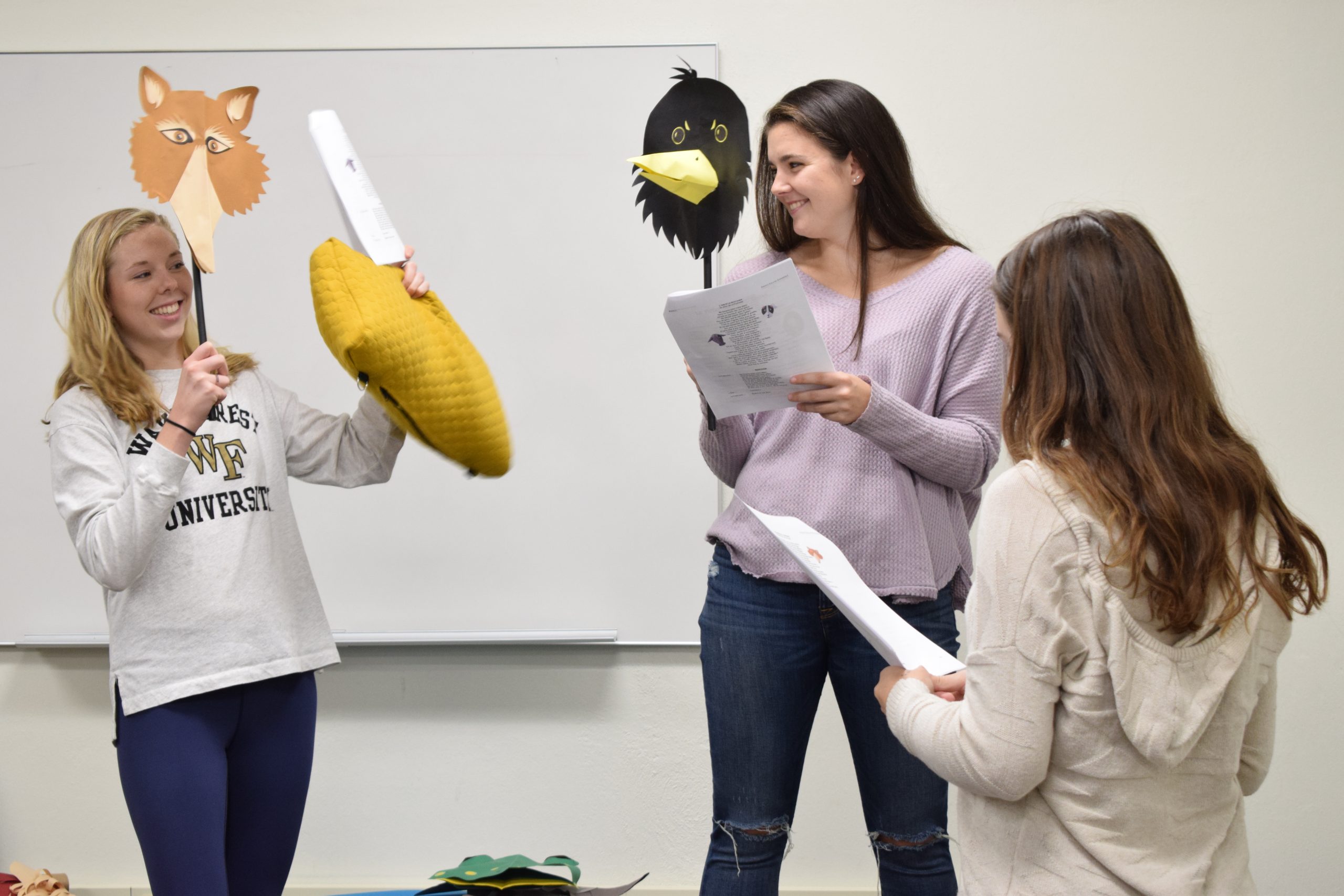 Students acting out French fables with paper puppets in class