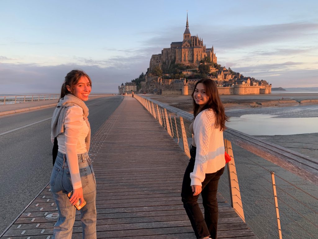 Two students facing camera with Mont Saint Michel in background