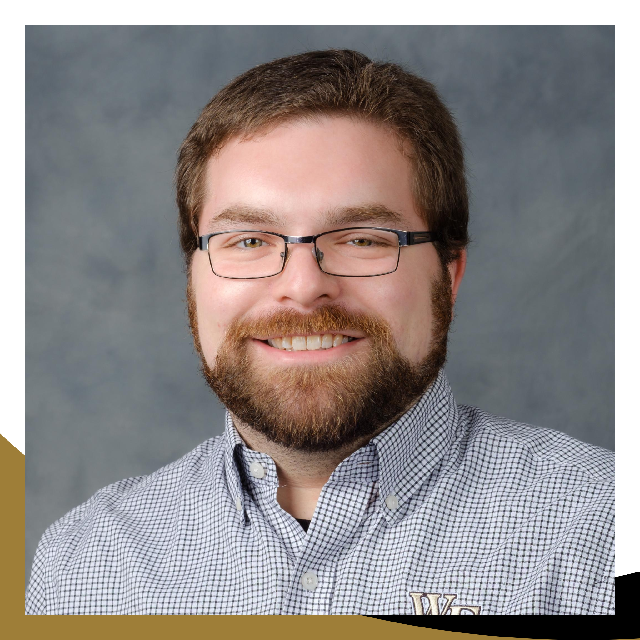 Photo of Trey Frye, who has a mustache and beard, and is wearing glasses and a gray shirt with a Wake Forest logo