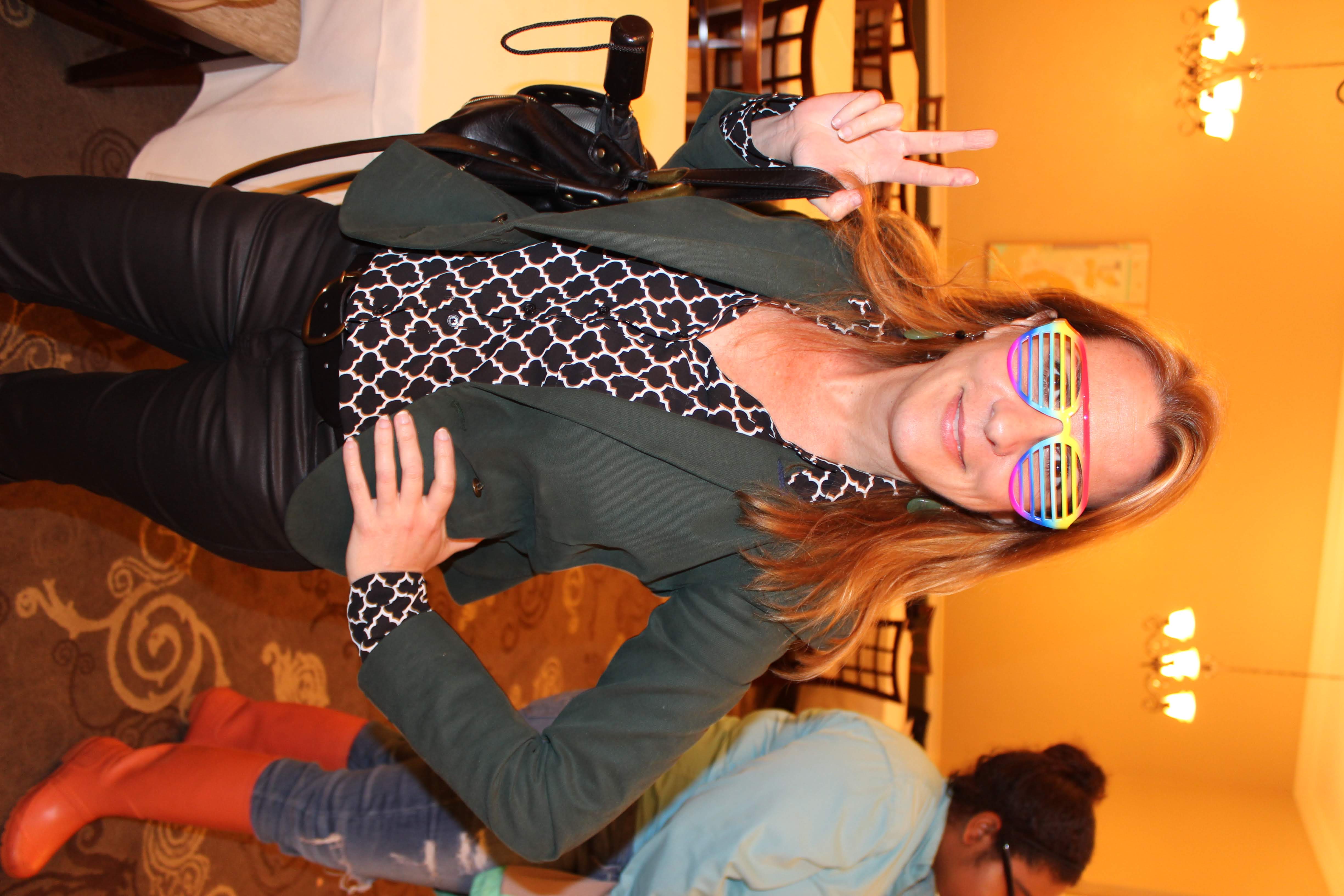 Individual showing peace sign while wearing rainbow glasses