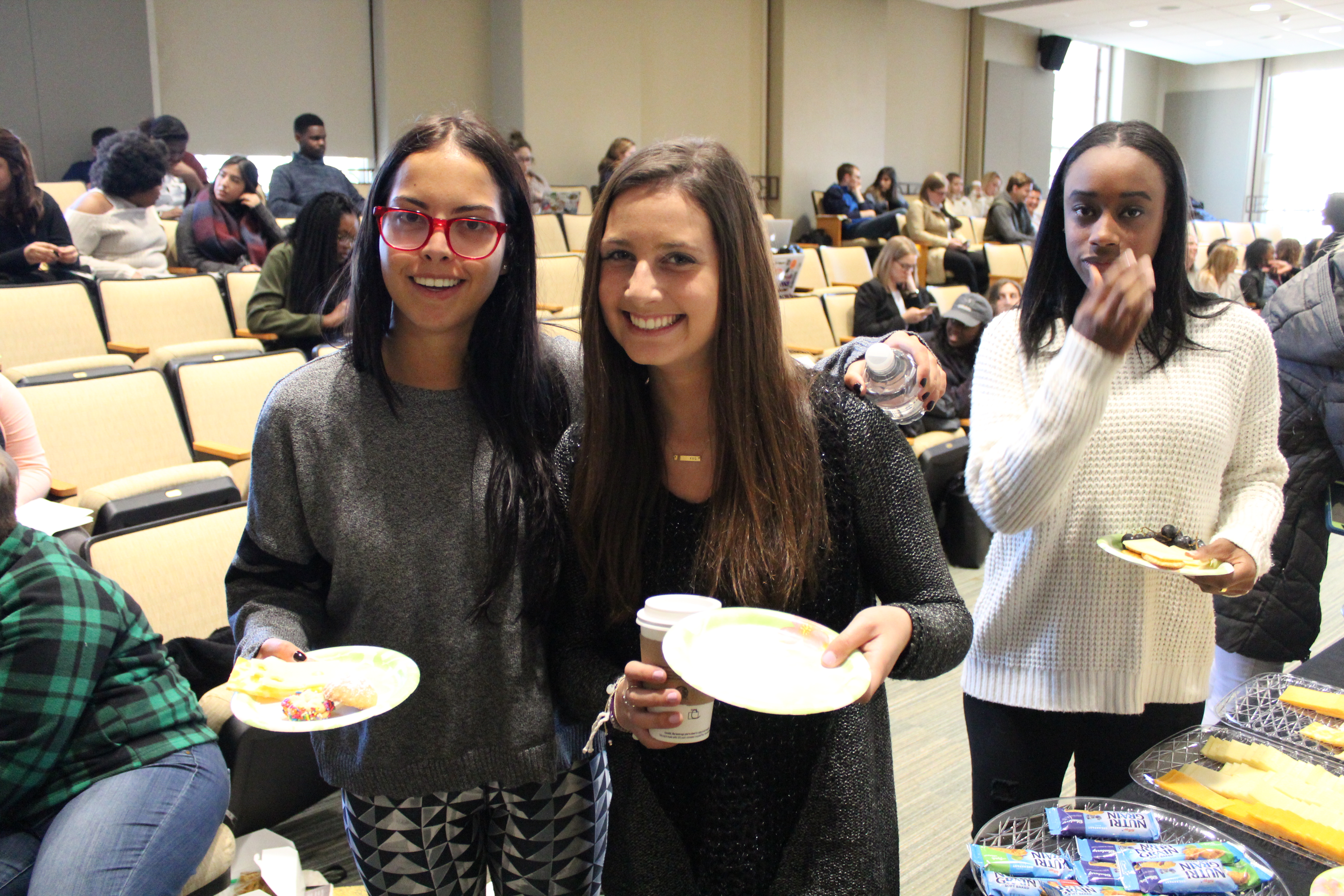 Two students smiling at camera holding plates of food