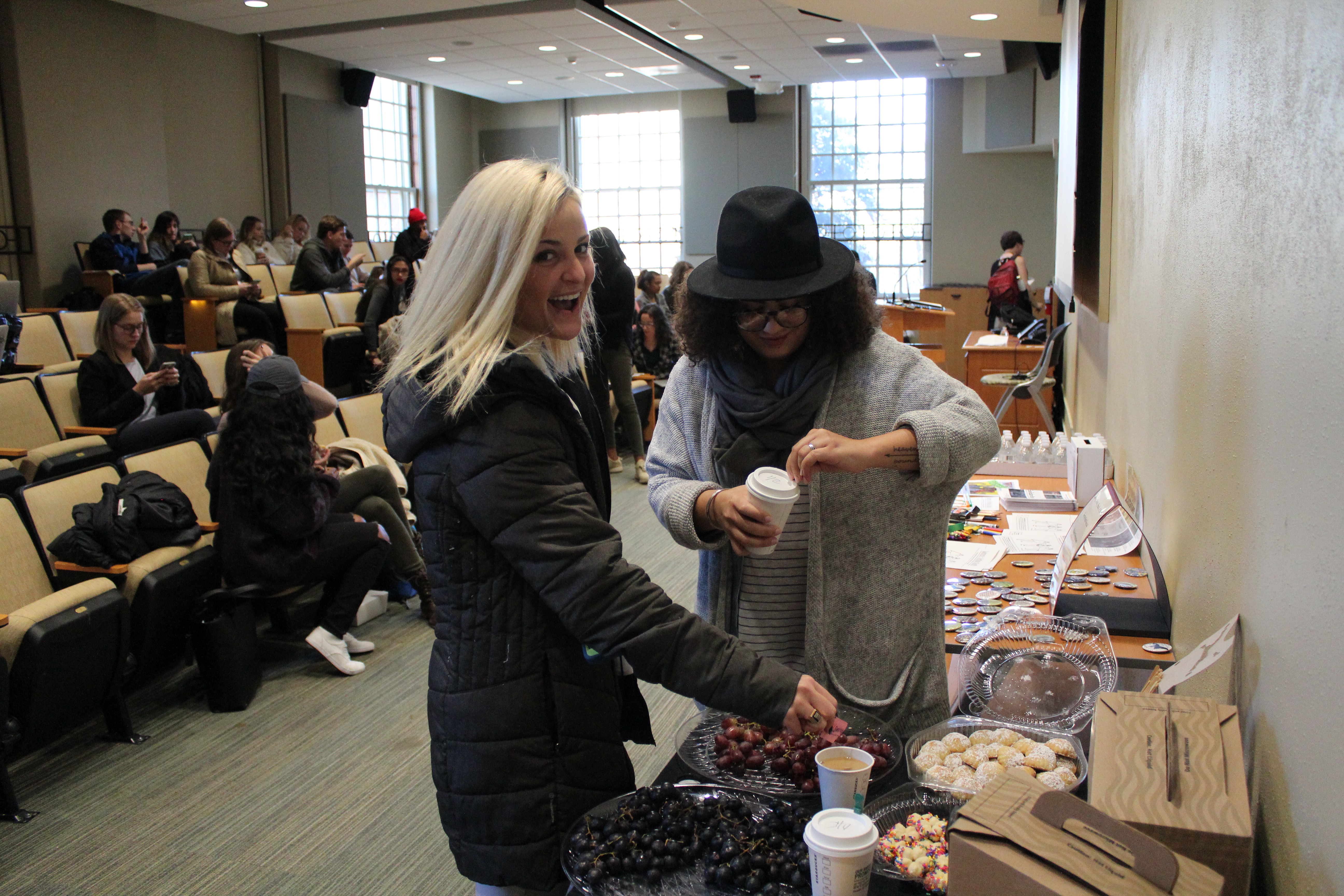 Two students at food table making coffee