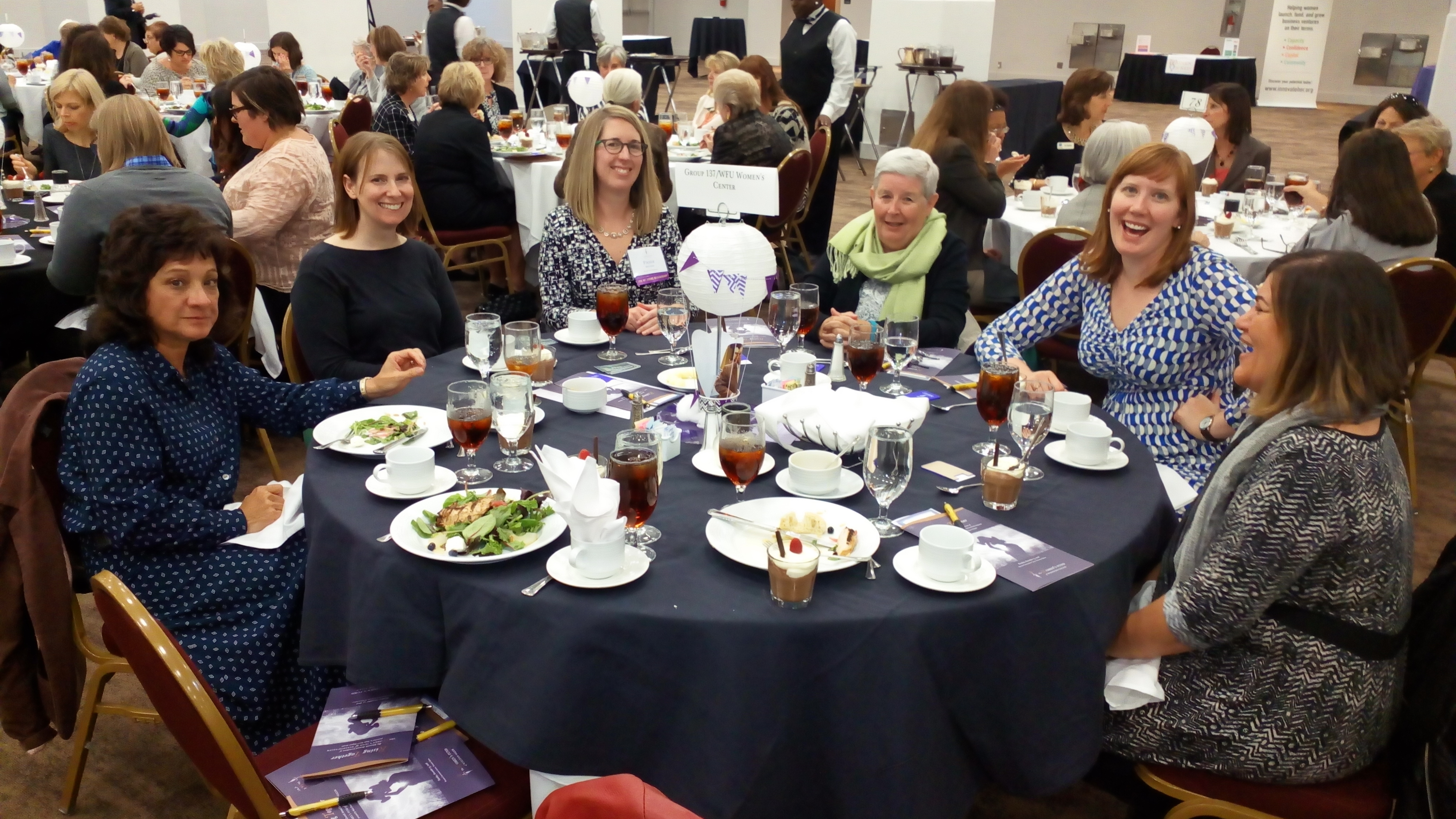 Group of women smiling and dining at circular table