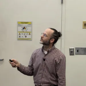 Lee Pryor holds a presentation remote while looking toward the screen during his M.S. defense talk.