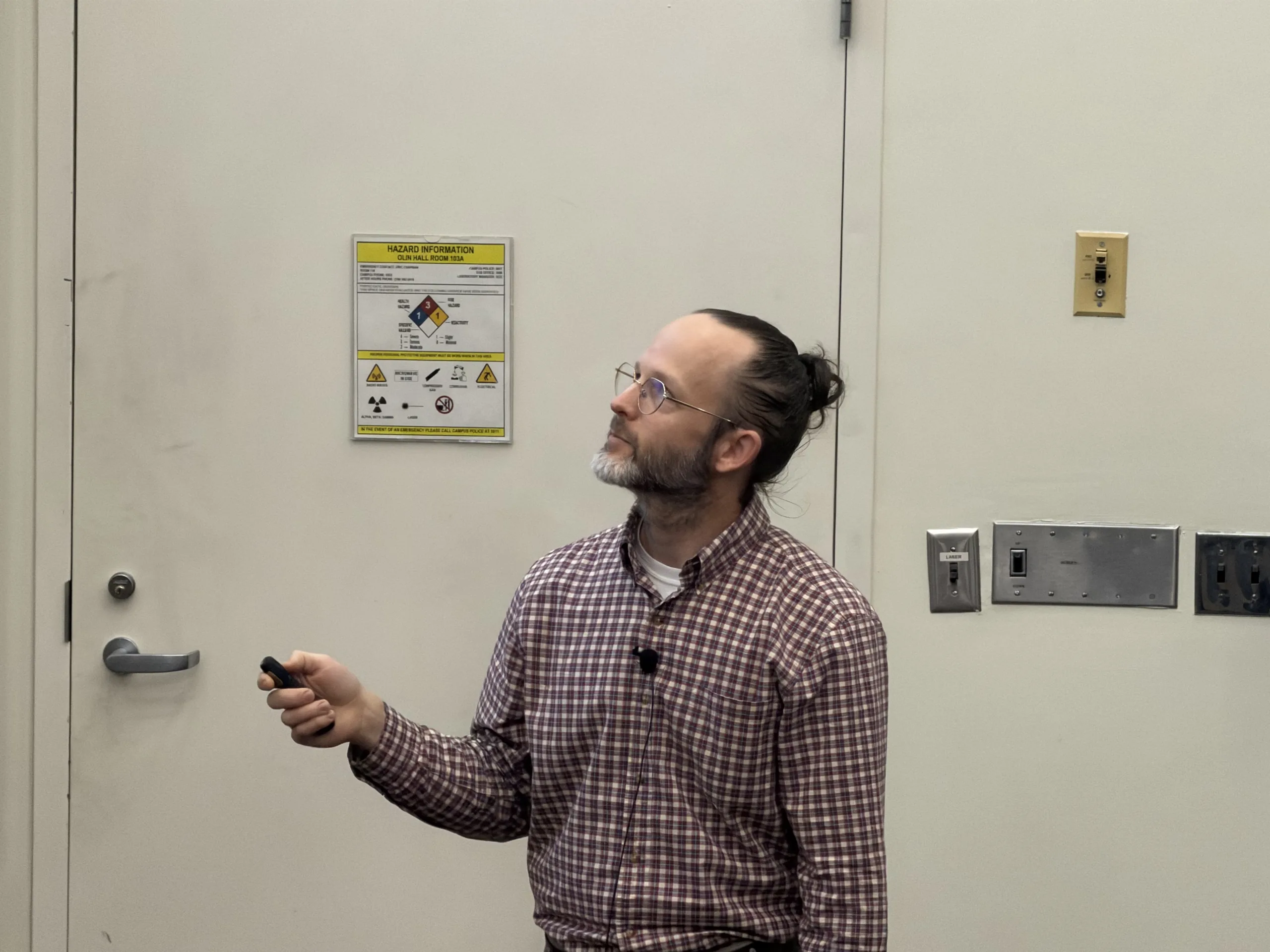 Lee Pryor holds a presentation remote while looking toward the screen during his M.S. defense talk.