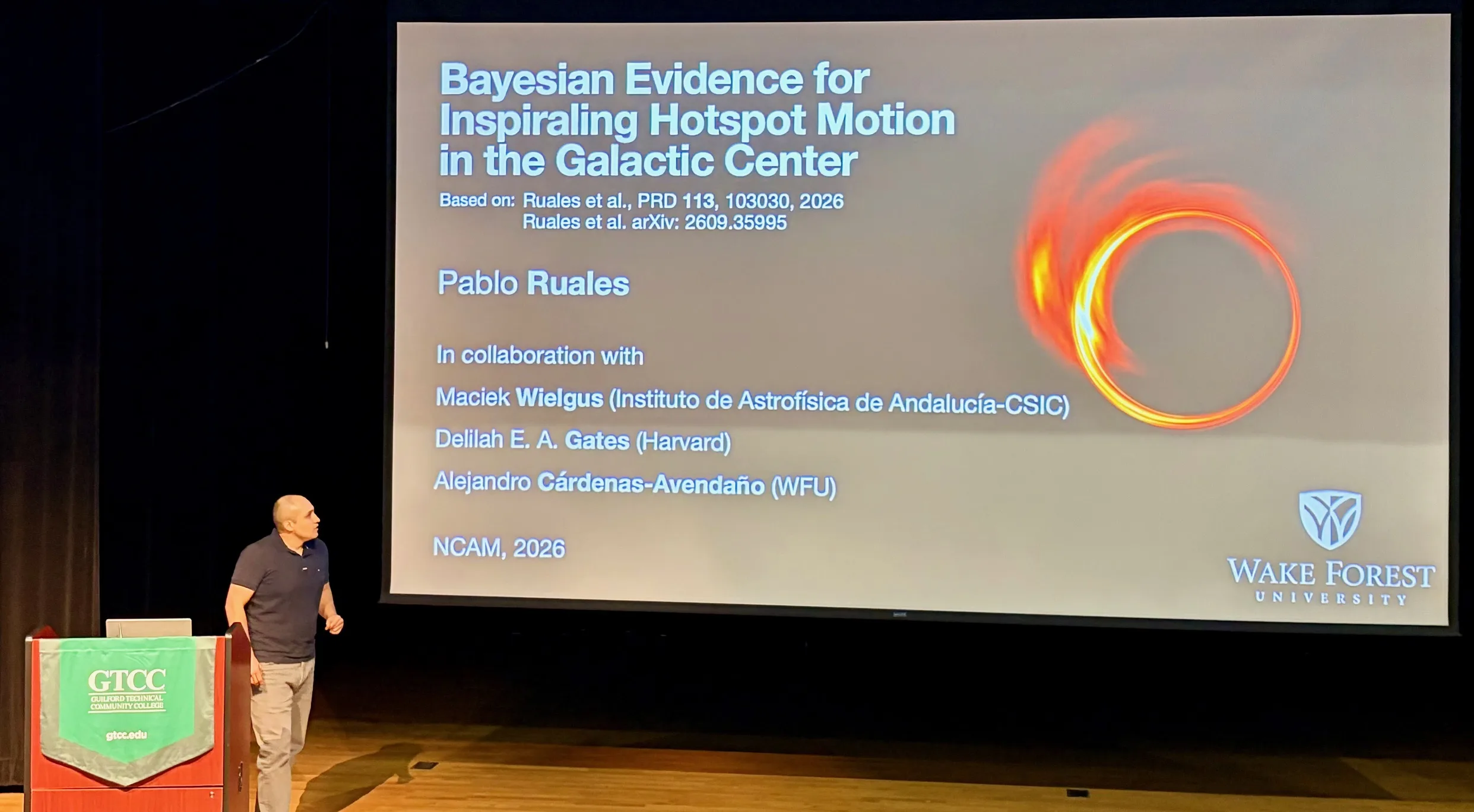 Pablo Ruales stands beside a projected slide titled “Bayesian Evidence for Inspiraling Hotspot Motion in the Galactic Center” at NCAM 2026. The slide includes a bright ring around a black hole and a Wake Forest University logo.