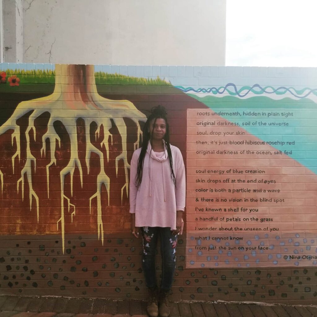 Nina Oteria stands in front of her poem on the Corcoran Poetry Wall in Durham, NC