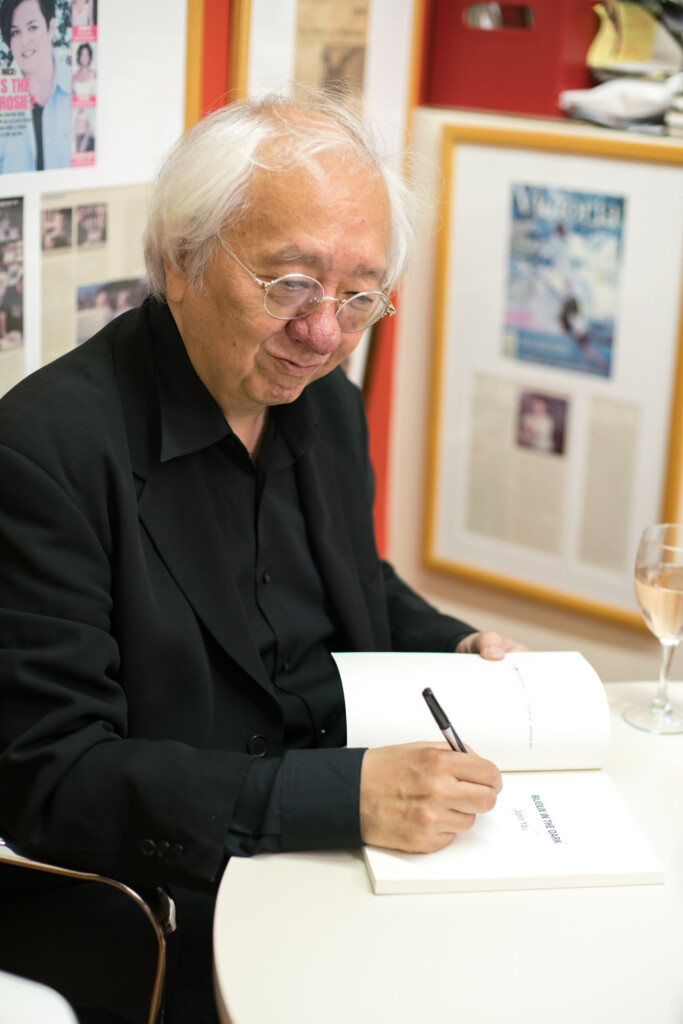 John Yau, seated, signs one of his books