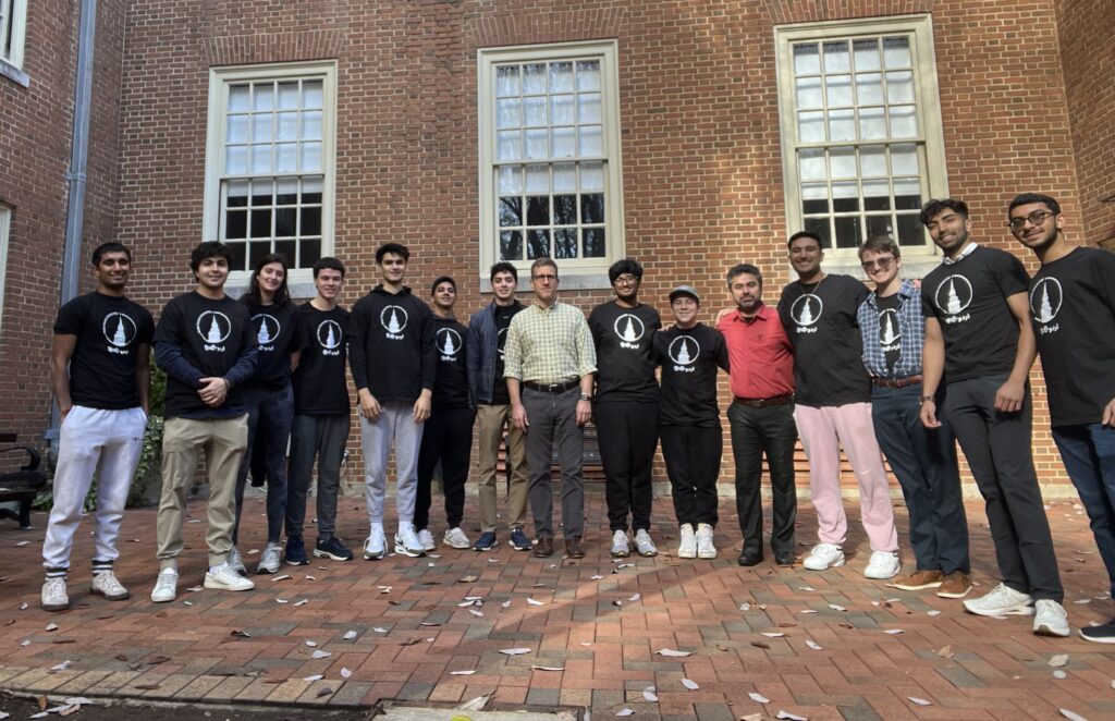 13 Hindi-Urdu students pose with their professors outside Tribble Hall in Fall 2023. The students are all wearing black and white Hindi-Urdu program t-shirts. 