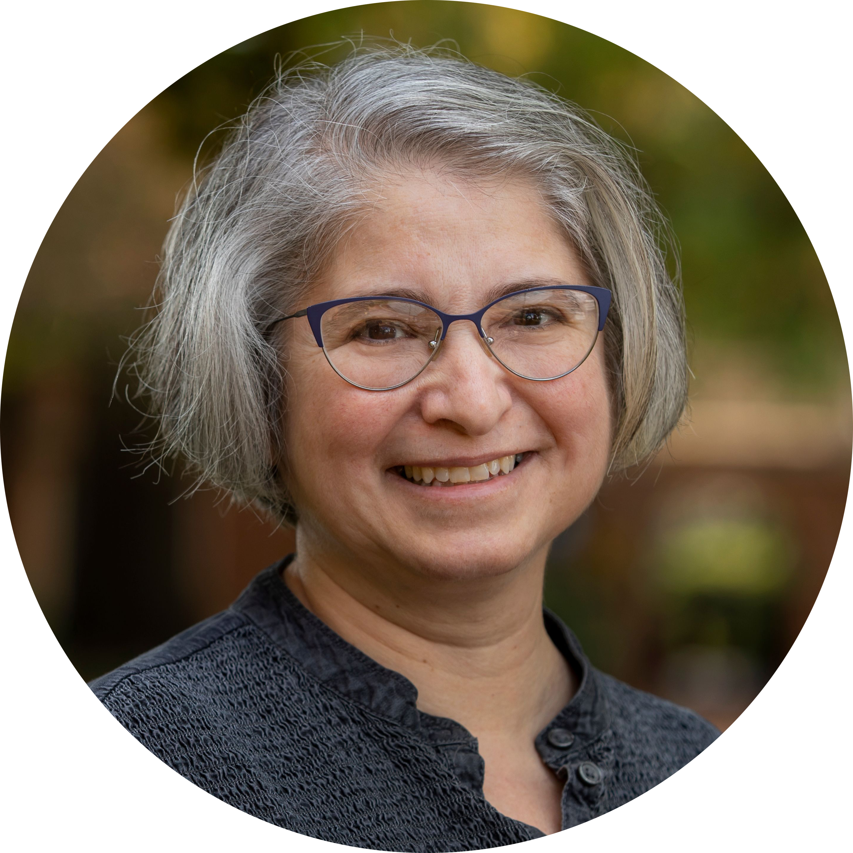 Profile picture of Amy Cohen: a white woman with cheek-length graying brown hair and glasses, smiling, wearing a black v-neck blouse.