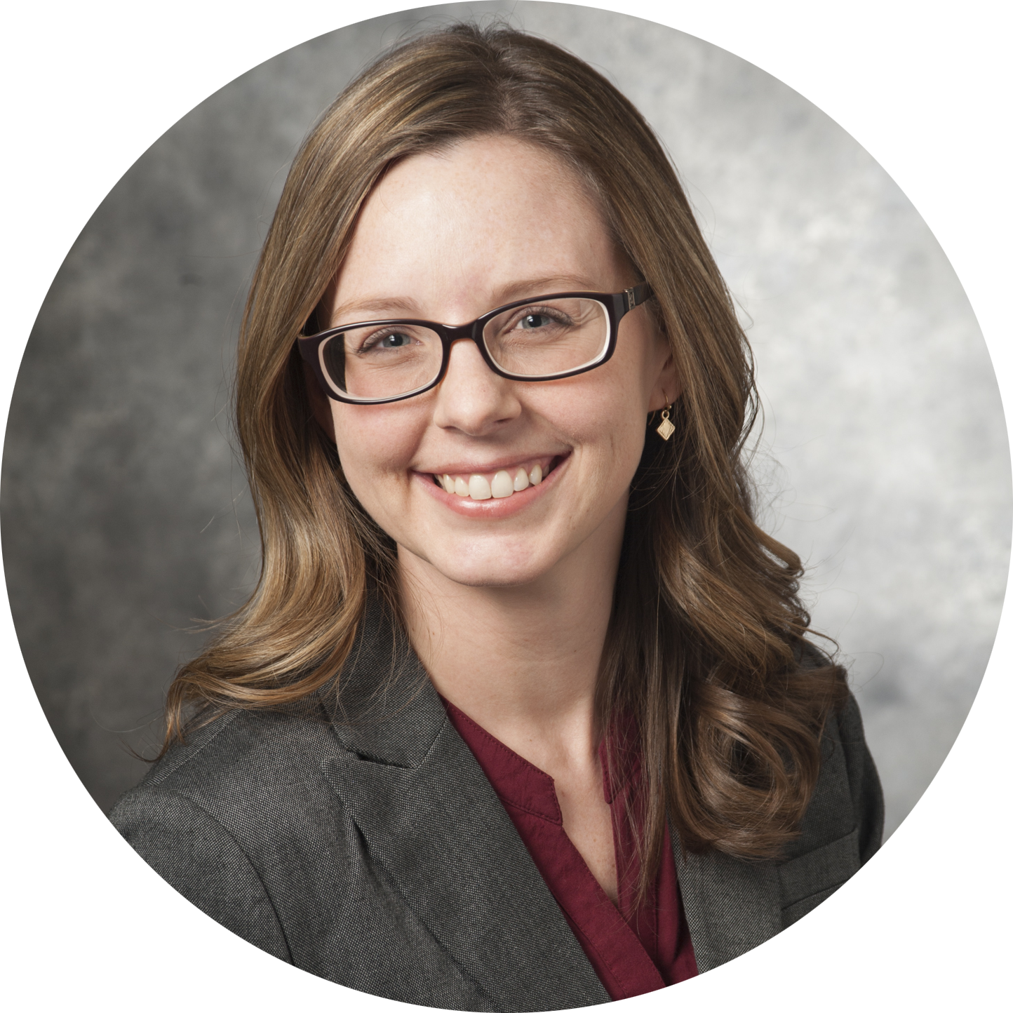 Profile picture of Carrie Johnston: a white woman with long straight brown hair, curled at the bottom, and glasses. She is smiling and wearing a gray blazer over a red v-neck.