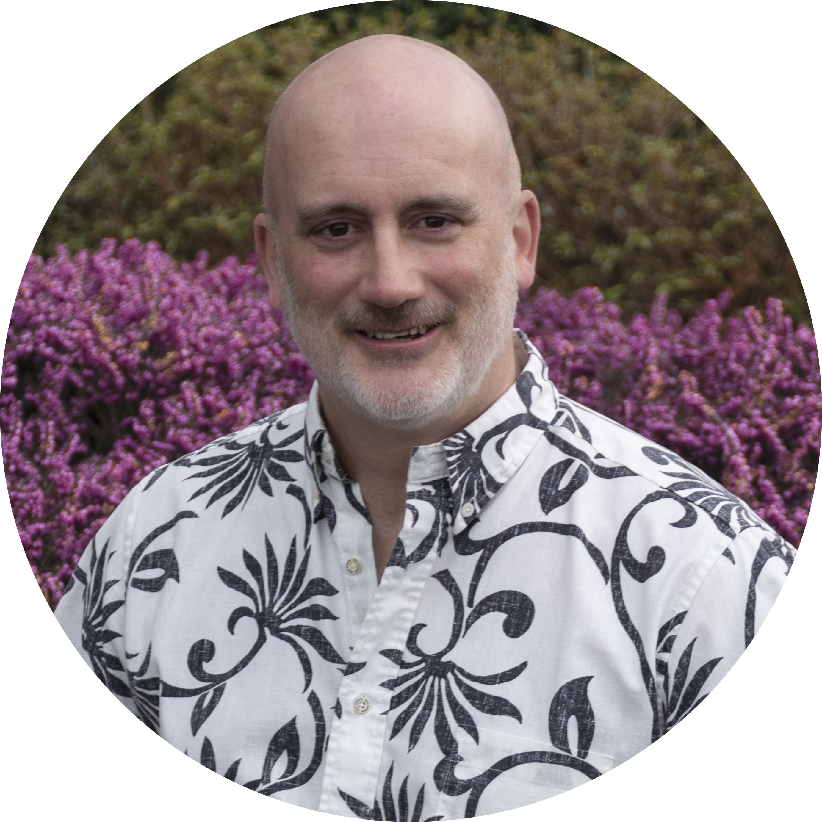 Profile picture of C. W. Marshall: a bald white man with short white beard. He is wearing a floral button-up with the top two buttons undone. The background is pink flowers and green trees.