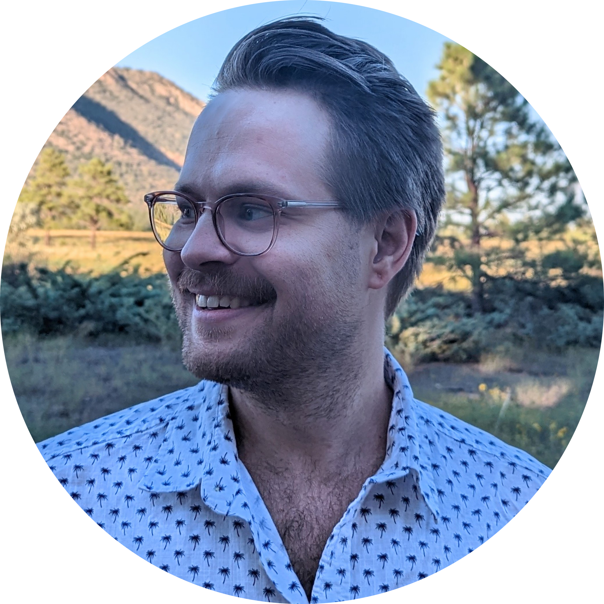 Profile picture of Shadow Zimmerman: a white man with graying brown hair and a stubbly beard. He is smiling and looking to his right; he is wearing a white button-up shirt with a palm-tree print.