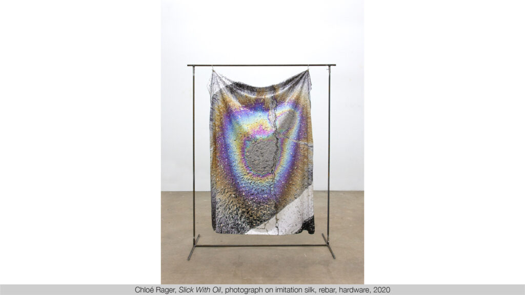 silk suspended from a rebar rectangular frame, featuring a spiral image of iridescent colors on pavement